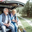 senior couple sitting at the car trunk