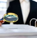 male auditor in suit using magnifying glass to check irs tax audit file on table