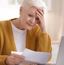 upset senior lady reading bills having financial troubles