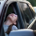 woman sitting in driving seat stuck in traffic looking out of window in frustration