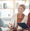 African American couple shaking hands with female financial advisor at home