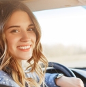 woman sitting in driving seat in car smiling while looking back