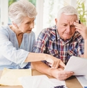 senior couple sitting at table reviewing taxes while doing calculations 