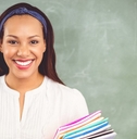 A woman teacher stands in front of a chalkboard holding a pile of colorful folders. She&#x27;s smiling.