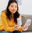 woman sitting on couch at home holding money 
