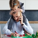 daughter sitting on her dads shoulders while he&#x27;s working on his laptop
