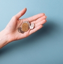 womans hand holding a heap of coins