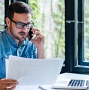 manager reviewing documents while talking on smartphone