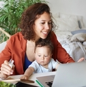 Woman holding baby looking at laptop