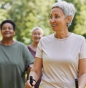 active senior woman walking with poles and smiling outdoors