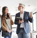 senior real estate agent showing around new modern house to young couple