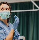 nurse putting on gloves in hospital room