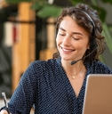 female customer service representative at office using laptop writing on notepad