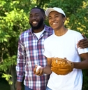 happy father praising son playing baseball in park