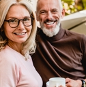 pleased senior couple smiling with cups of coffee