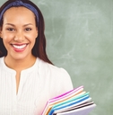 smiling school teacher holding books in classroom
