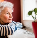 sad senior woman looking through window