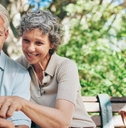 senior couple looking at map in hand while sitting on bench 