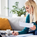 woman sitting on couch at home writing on papers to file tax