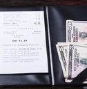 A restaurant bill with a cash tip set to the side. 