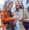 two beautiful senior females laughing in street