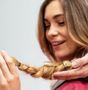 woman at hair salon cutting her hair short to donate it to cancer patients