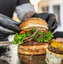 chef wearing black disposable gloves preparing fresh burgers on grill.