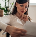 mature woman sitting on couch at home reviewing bills 