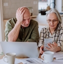 Stressed senior couple calculate expenses or planning budget together while sitting on the table with documents and laptop at home.