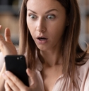 woman shocked at news on smartphone