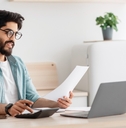 young man calculating taxes using calculator