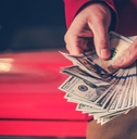man counting money over vintage car