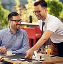male waiter serving food to couple