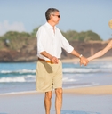 happy senior couple walking on beach
