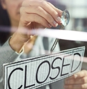 woman hanging closed sign on door