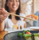 women eating sushi using chopstick