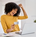 Happy woman holding a credit card and cheering