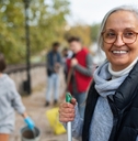 cheerful senior female volunteer cleaning street