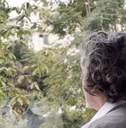 elderly woman looking out window longingly