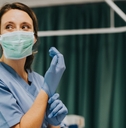 Nurse wearing gloves in hospital room