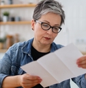senior woman reading bills in kitchen