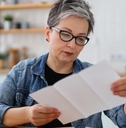 senior woman reviewing bills in kitchen 