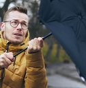 man holding broken umbrella