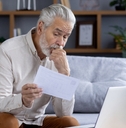 upset senior man reviewing bills