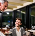 senior waiter serving couple at restaurant