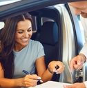 happy woman buying car at showroom