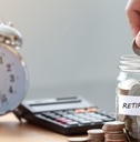 hand putting coins in retirement jar