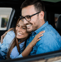 A man and woman hug one another in a car. 