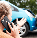A woman talks on her phone in front of a fender bender.
