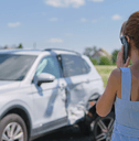 A woman stares at her totaled car.